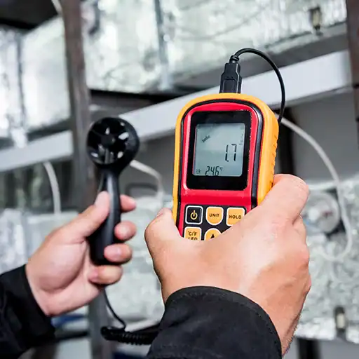 Technician measuring temperature with digital thermometer in HVAC system.